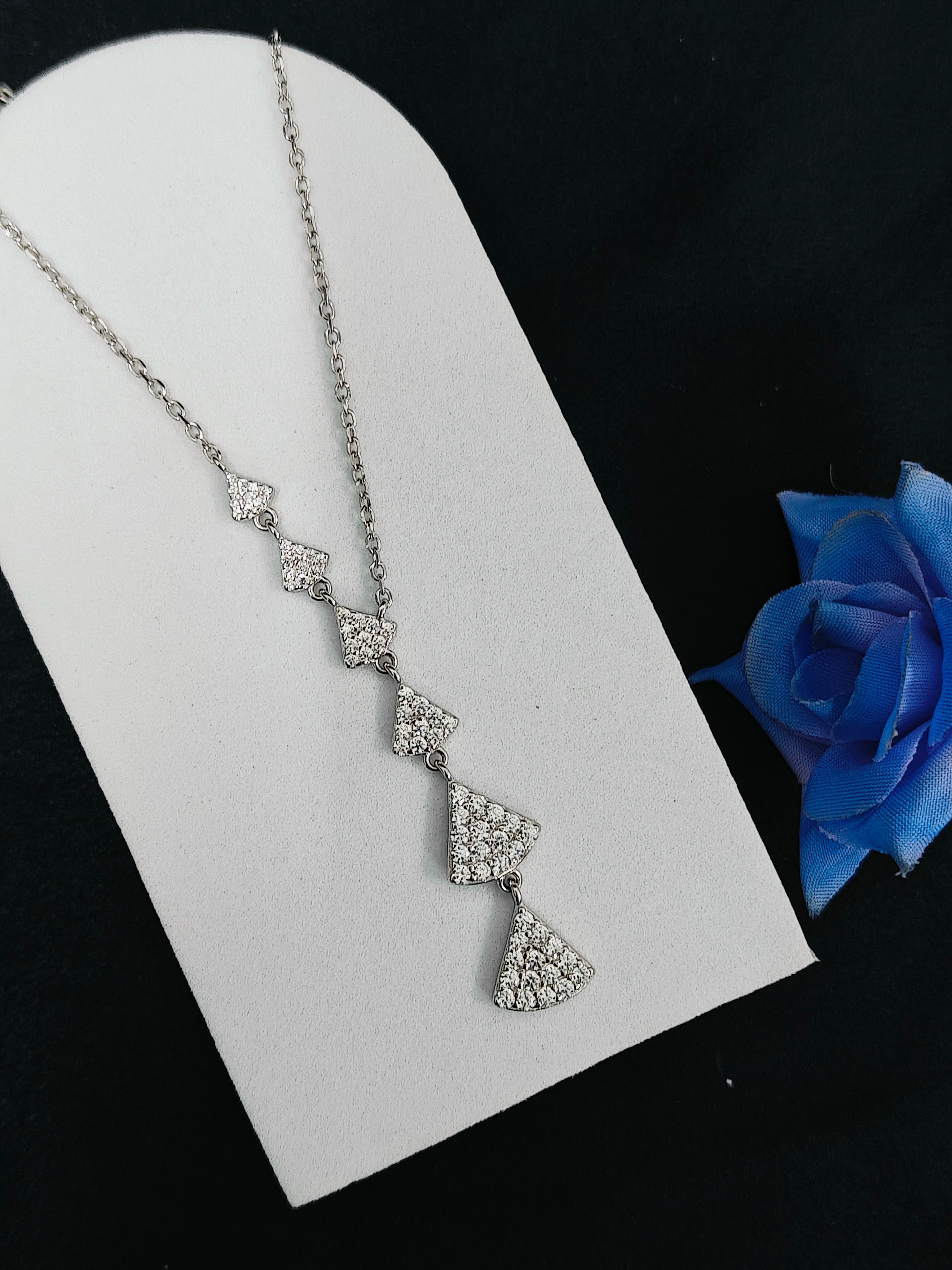 Silver necklace with a blue rose on a black background